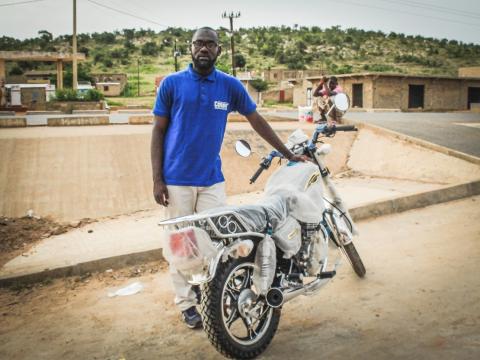 Un homme debout tenant une moto à la main